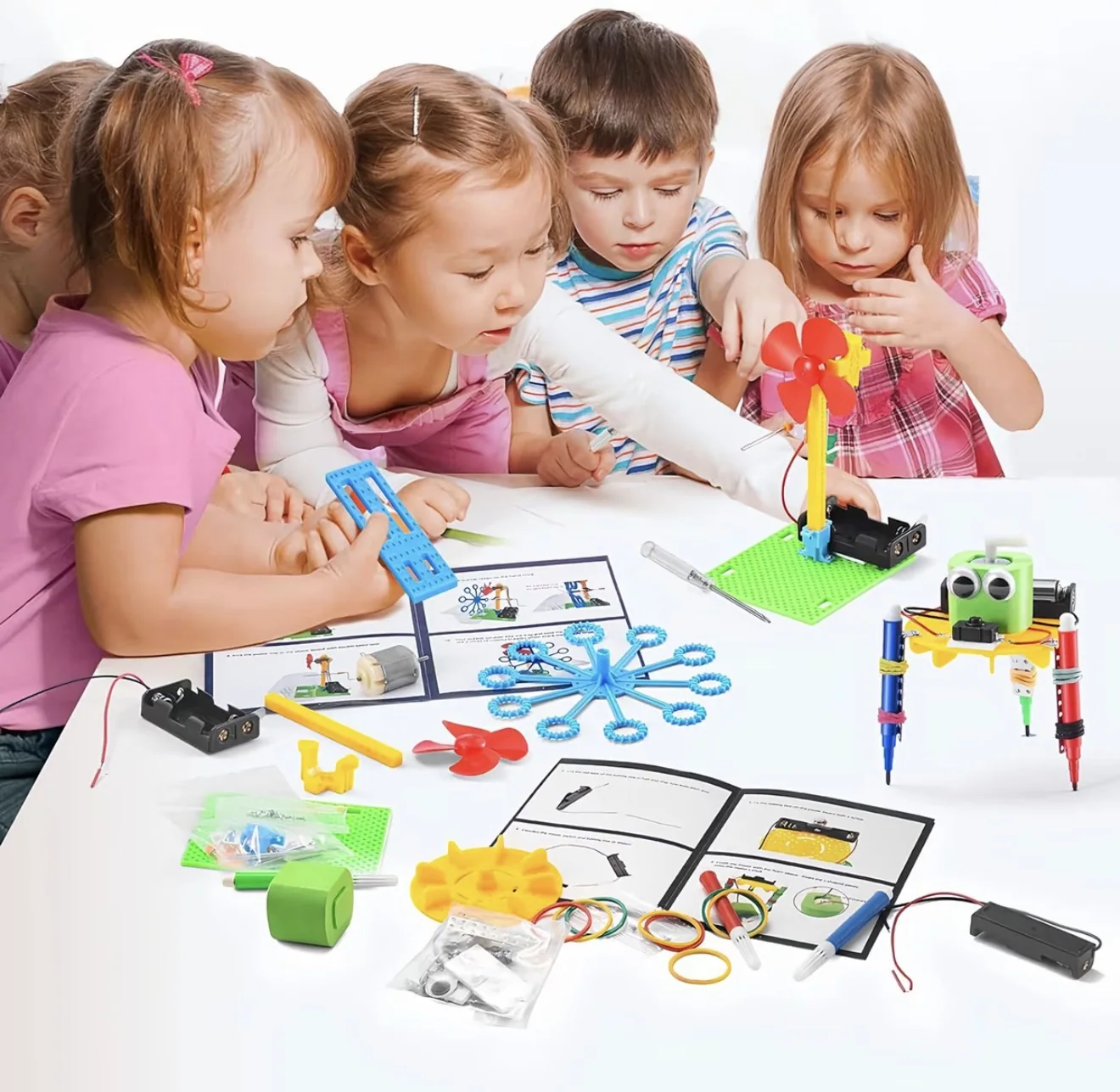 Grupo de crianças montando os projetos do kit juntas, com peças e manual sobre a mesa